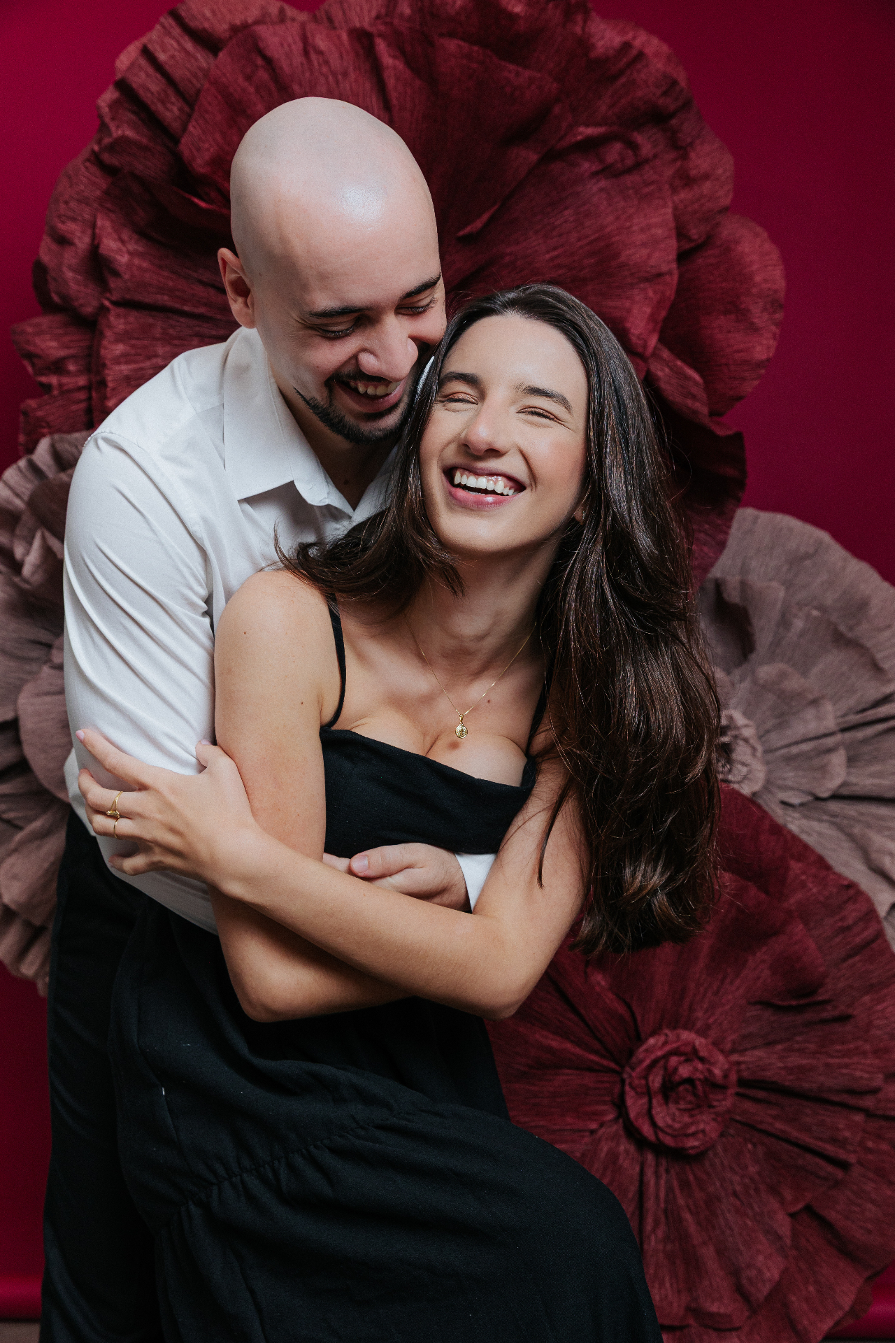 Casal rindo em meio a grandes flores de papel